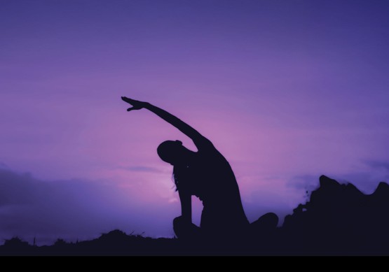 Woman doing yoga outdoors at sunrise